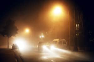 Car driving in fog with headlights on