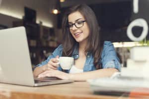 Woman with glasses drinking coffee at a desk